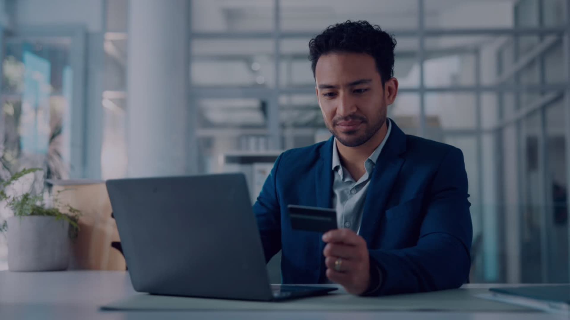 Profissional utilizando notebook e cartão em escritório